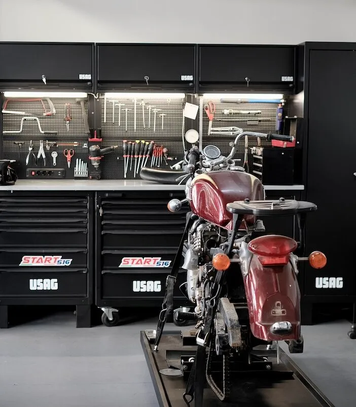 Μοτοσυκλέτα Triumph σε ανυψωτικό μπροστά από τον πάγκο εργαλείων